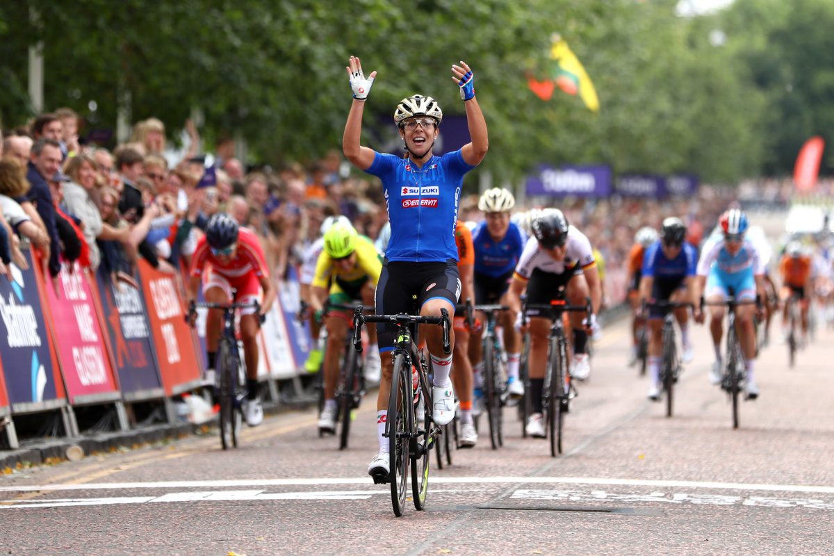 Bicycle race, winner raises his hands in the air, chasers come riding right after him