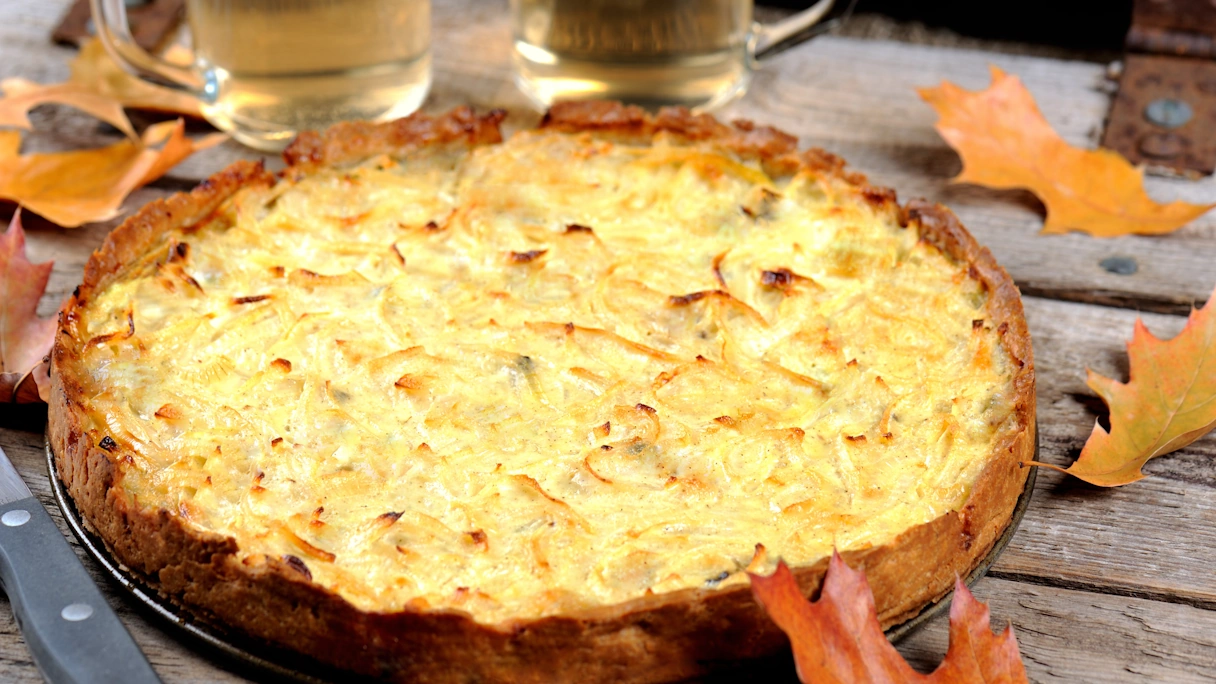 Zwiebelkuchen mit zwei Gläsern Weißwein