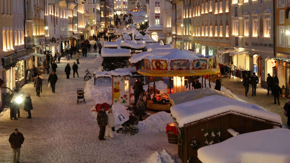 Der Christkindlmarkt in Bad Tölz in der Marktstraße. Es liegt Schnee und es laufen viele Menschen durch die Straße