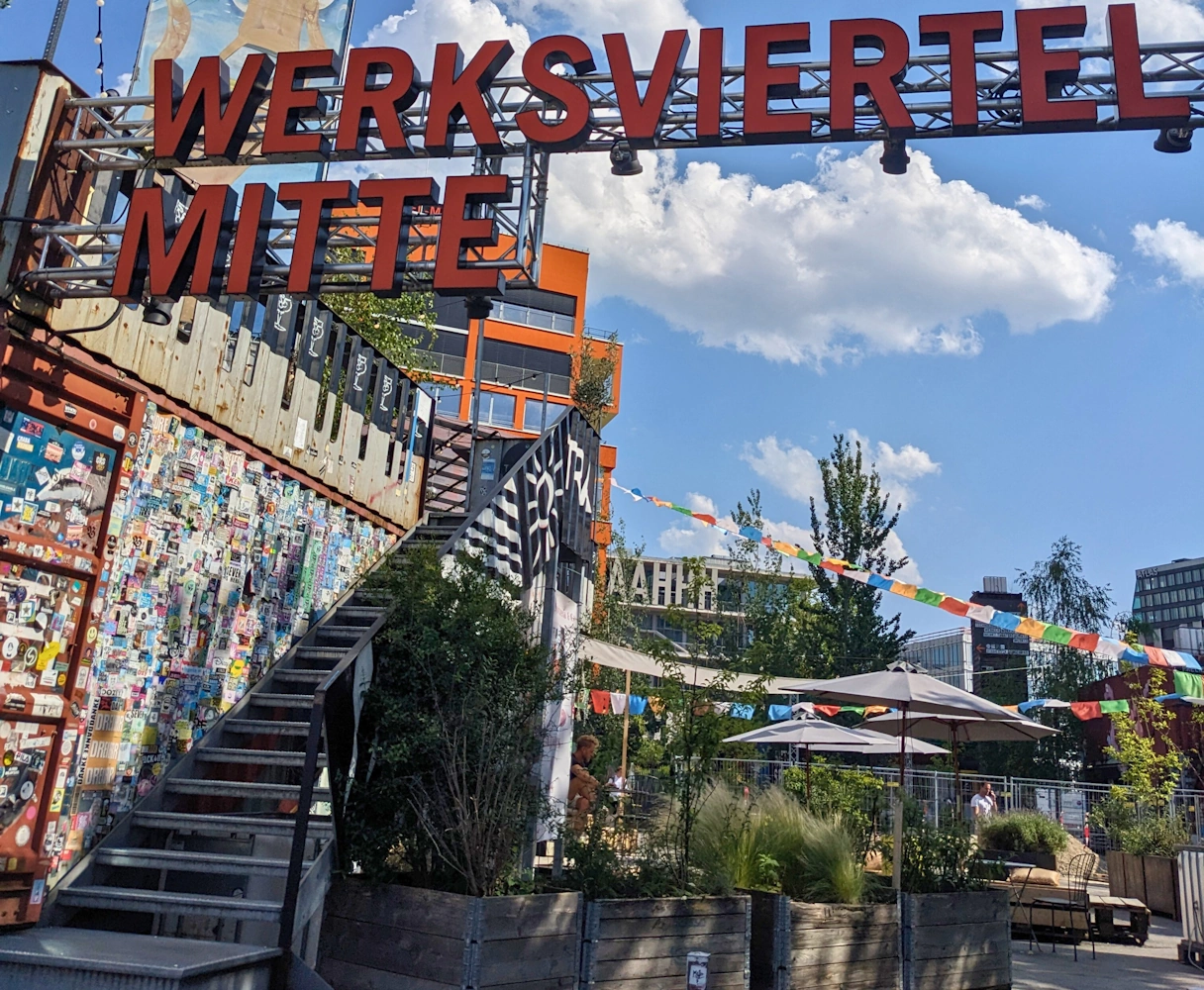 Eingang des Werksviertel Mitte, Draußenbereich mit bunter Deko und Bars/Restaurants