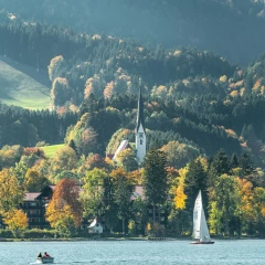 Blick auf den Tegernsee mit Booten und Wald im Hintergrund