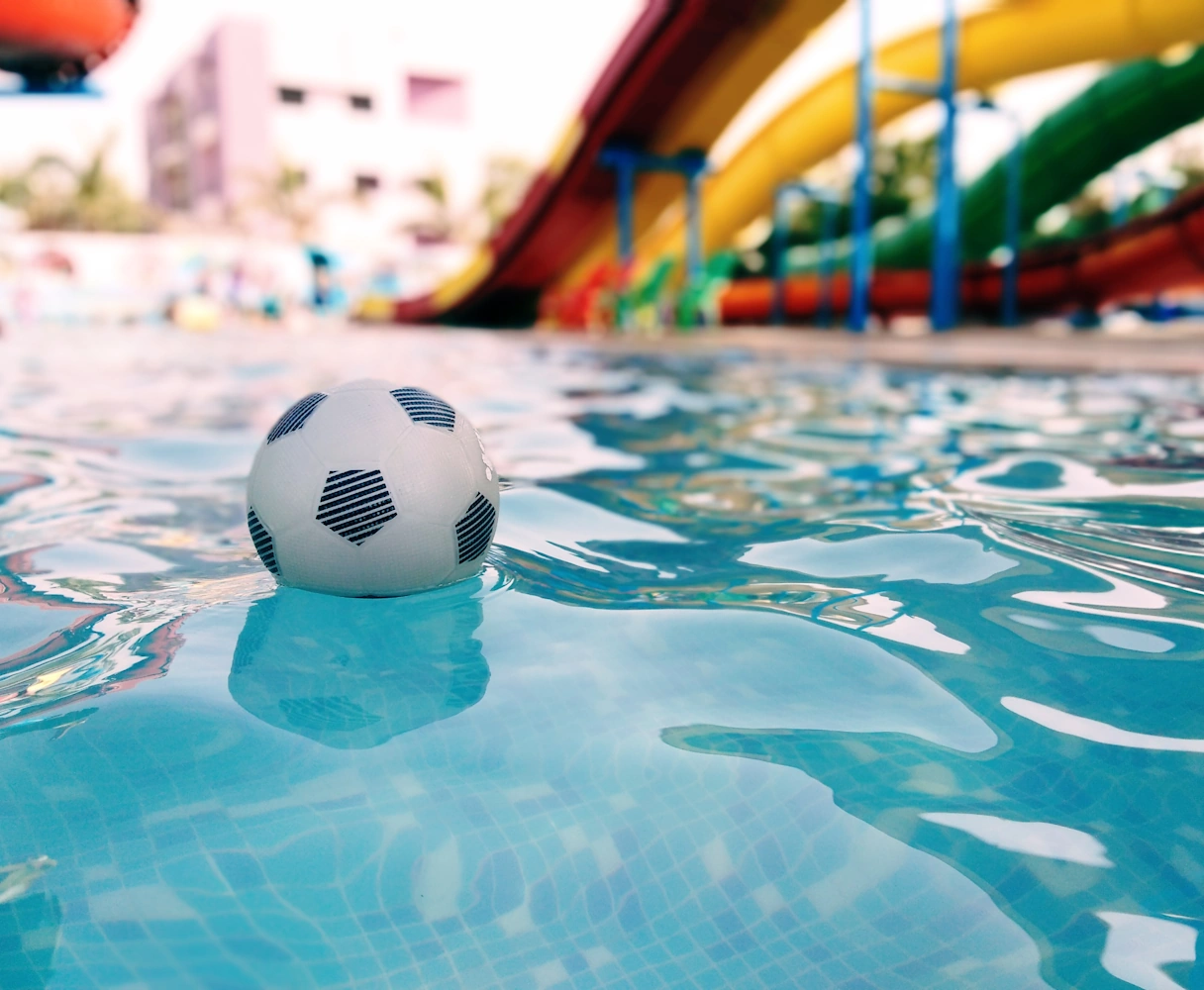 Children's area in the outdoor pool, ball lying on the water, slide in the background