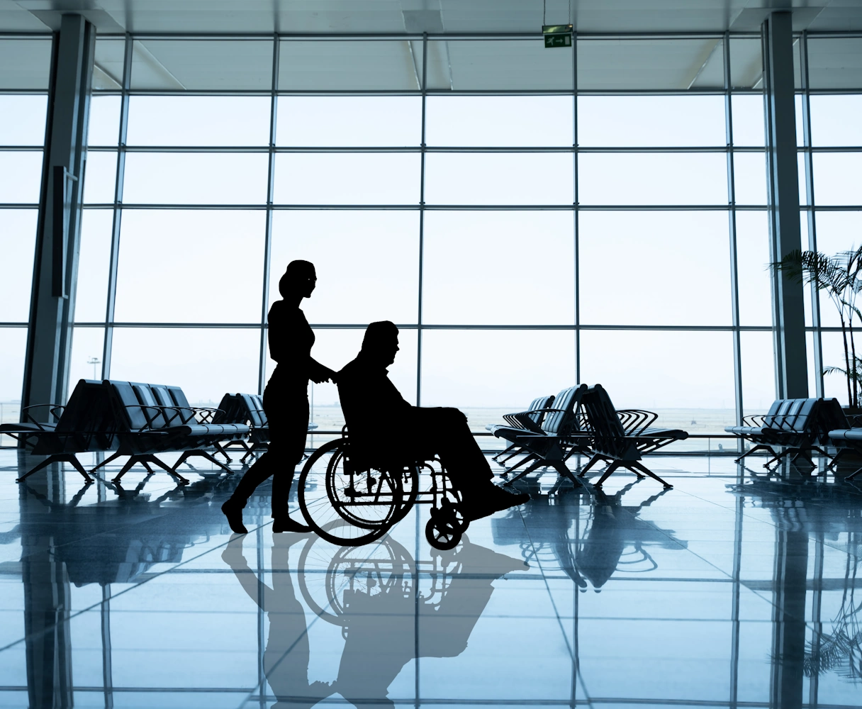 Rollstuhlfahrer am Flughafen wird von einer Person geschoben