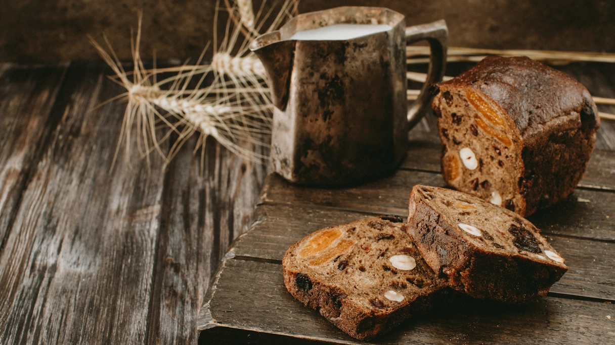 Bread filled with nuts and fruit placed on a wooden base and cut open