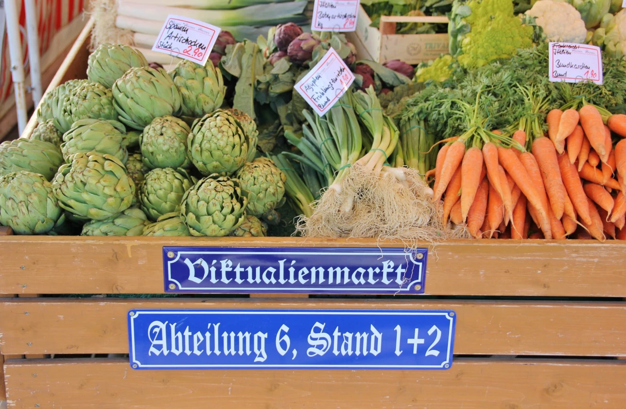 Viktualienmarkt München, Gemüsestand, Mohrrüben, Artischocken und Lauchzwiebeln liegen in der Auslage