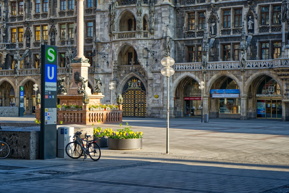 Part of the Marienplatz. The sun is shining, there are no people to be seen, on the left is the entrance to the underground and S-Bahn station. In the background is the new town hall