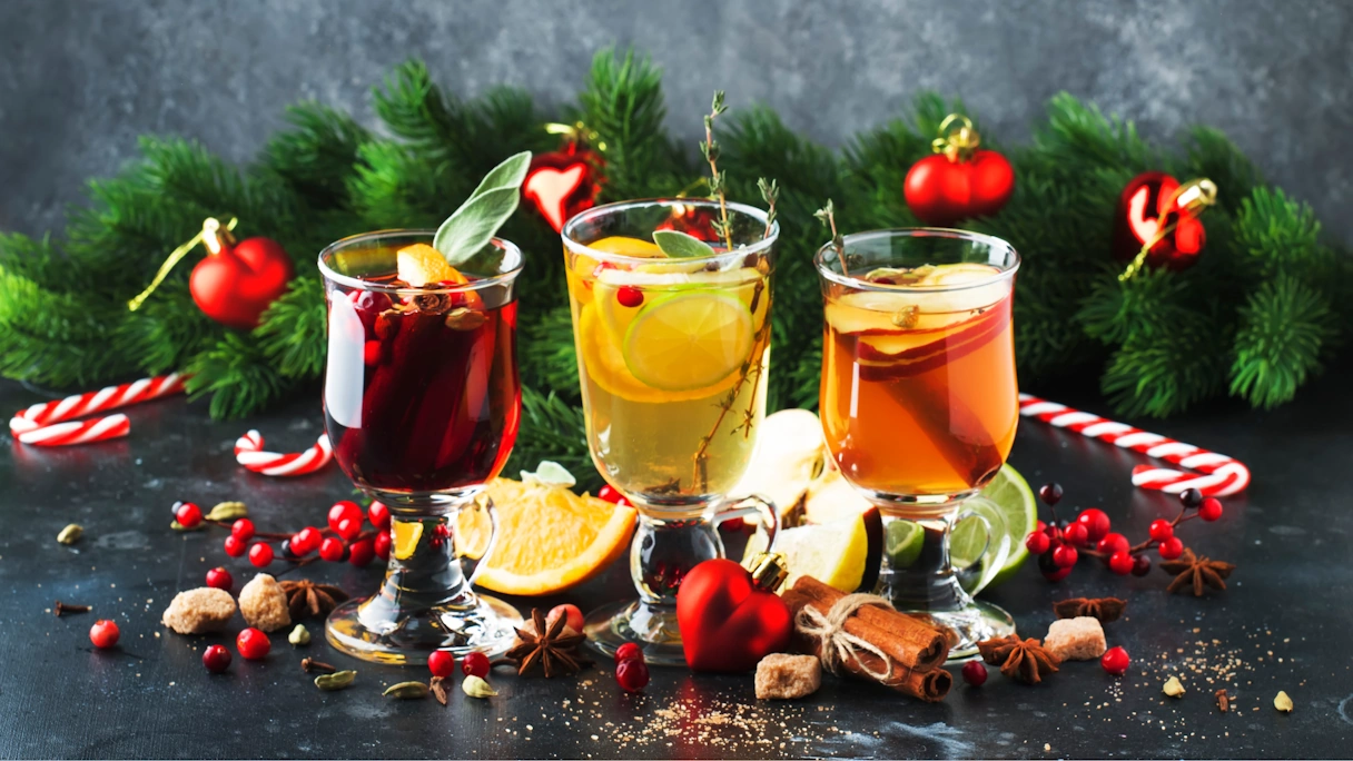 Various types of mulled wine, decorated with fir, fruit and candy canes