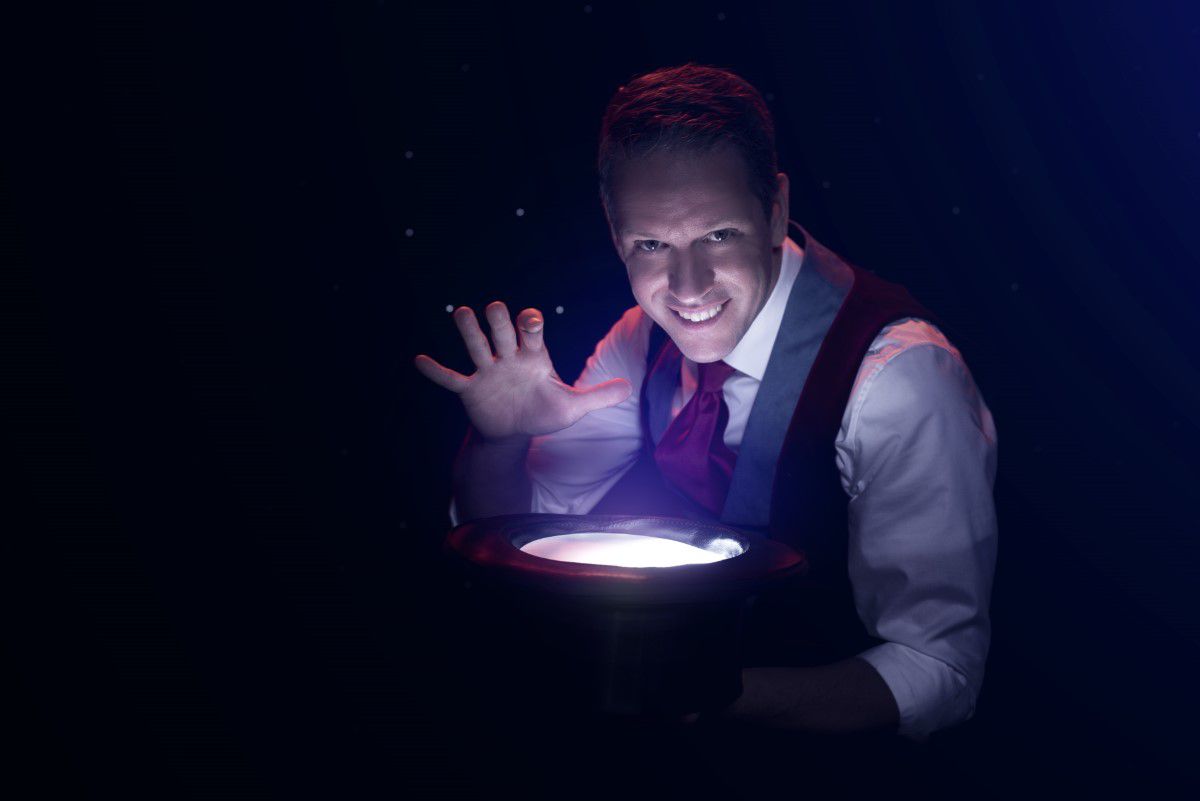 Alexander Krist, Mann im Anzug wird von einem Scheinwerfer angeleuchtet, lächelt in die Kamera