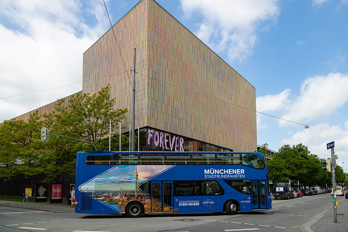 Gray Line Sightseeing, blauer Bus fährt um eine Straßenkreuzung in München