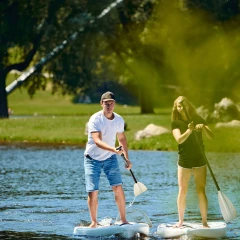 Ein Mann und eine Frau auf einem Stand Up Paddle auf dem Olympiasee in München