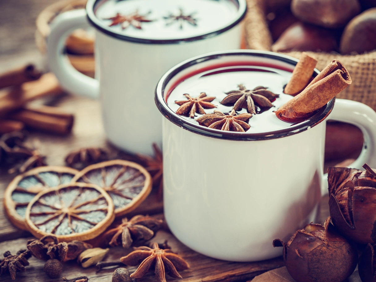 Zwei Tassen Glühwein mit Zimtstangen dekoriert und getrockneten Früchten