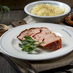 Zum Franziskaner, Leberkäse auf einem weißen Teller, Kartoffelsalat in einer Schüssel und Bretzel auf dem Tisch