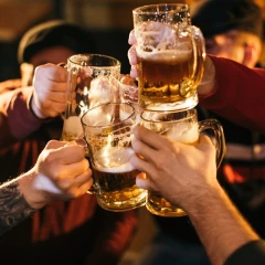 Vier Männer stoßen gleichzeitig mit jeweils einem Krug Bier an