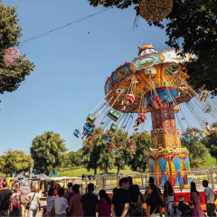 Sommerfest im Olympiapark, ein buntes Kettenkarusell dreht sich und viele Besucher schlendern über das Gelände
