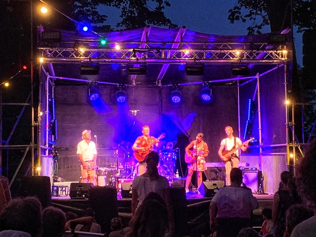 Band consisting of four people make music on a stage in the evening