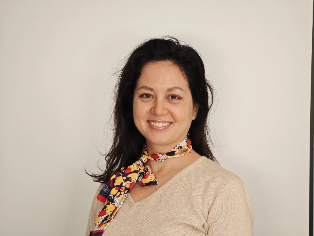 Portrait picture of Diana. She smiles at the camera and has a colorful scarf around her neck.