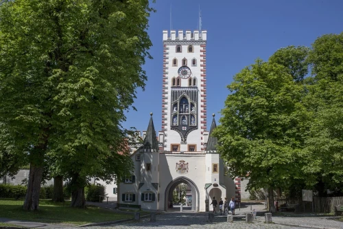 Blick auf das Bayertor im Sommer in Landsberg am Lech. Drum herum stehen viele grüne Bäume