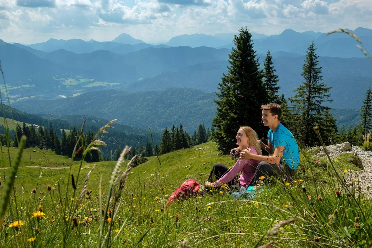 Young couple sitting in a meadow with mountains in the background