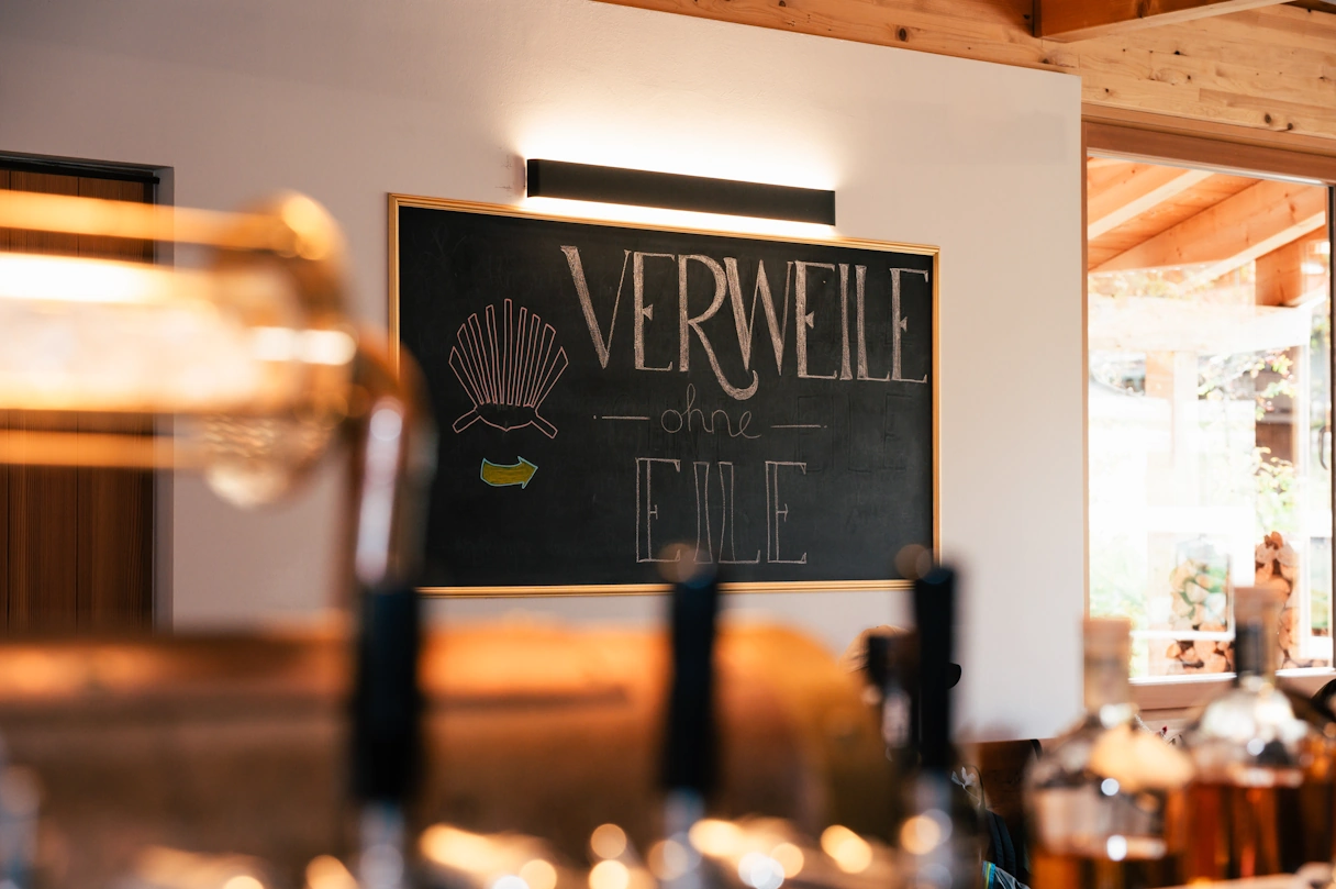 The plaque on the wall in the GenussVerweilerei restaurant. It bears the words “Linger without haste”