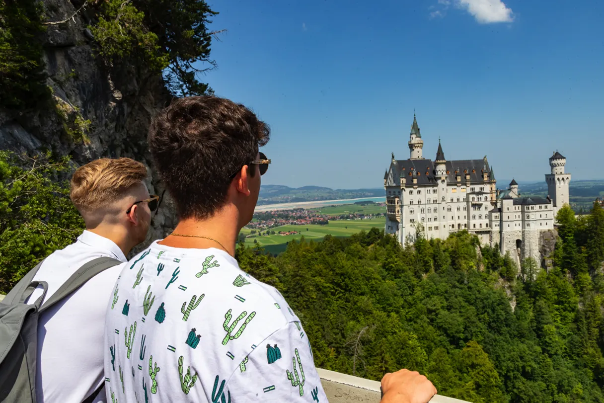 2 junge Touristen in Neuschwanenstein gucken auf Schloss im Hintergrund