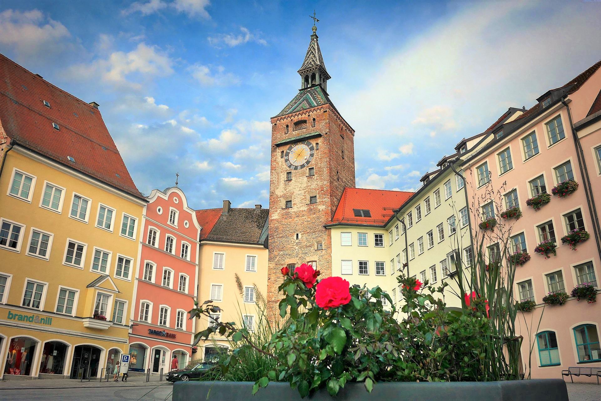The Schmalzturm on the main square in Landsberg am Lech. Colorful building facades, flowers, and a blue sky
