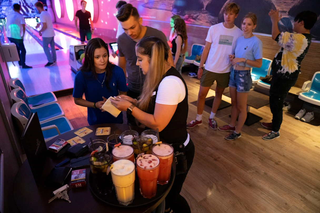 Employee serves the bowling guests with drinks at the seating areas of the bowling alley