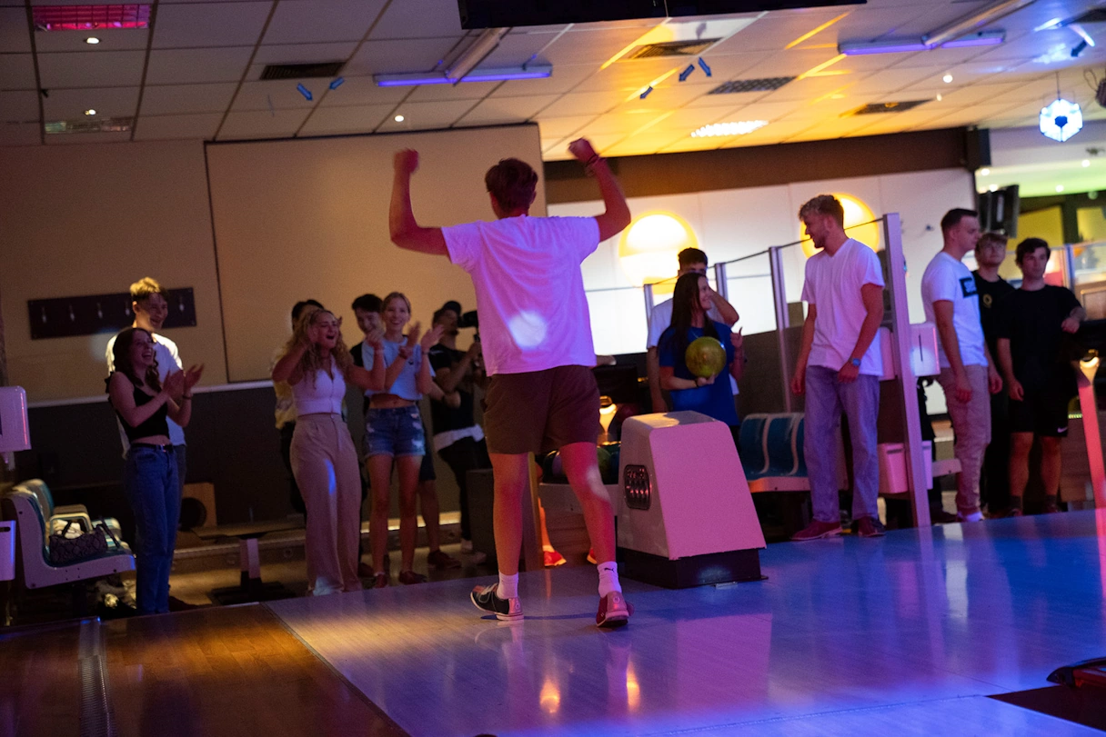 Young man raises his arms in joy while bowling