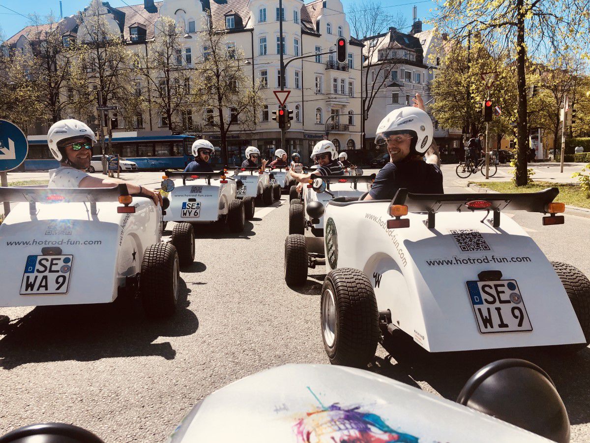 Hot Rod Fahrer in weißen Go Karts auf den Straßen Münchens in einer Reihe fahrend
