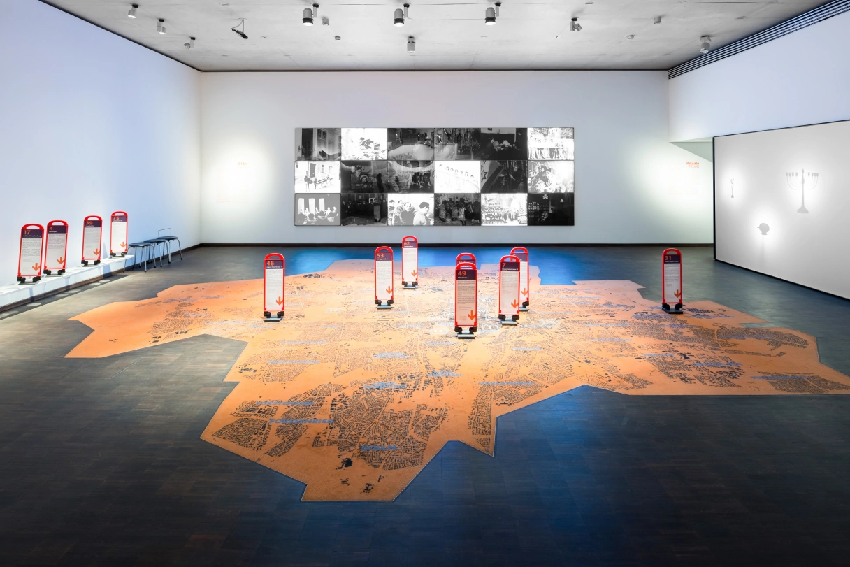 Dauerausstellung im Jüdischen Museum mit einer Karte auf dem Boden, Bildern an der Wand und Informationstafeln