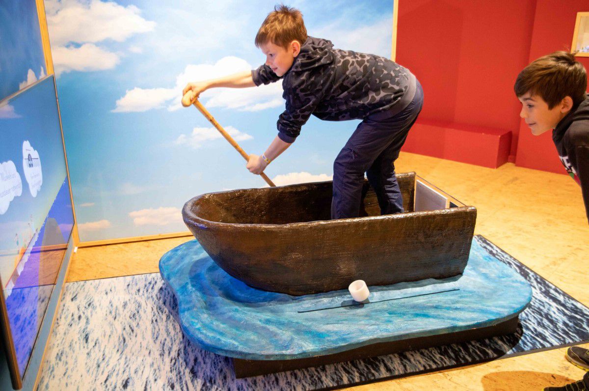 Boy in a small rowing boat in the children's museum at a tasting station