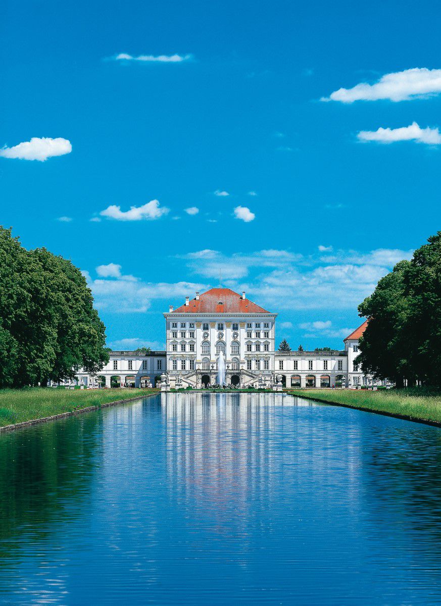 Das Schloss Nymphenburg mit kleinem See davor bei fast wolkenlosem Himmel