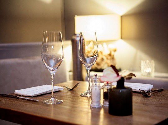 Gedeckter Tisch mit zwei leeren Weingläsern in Wohnzimmeratmosphäre