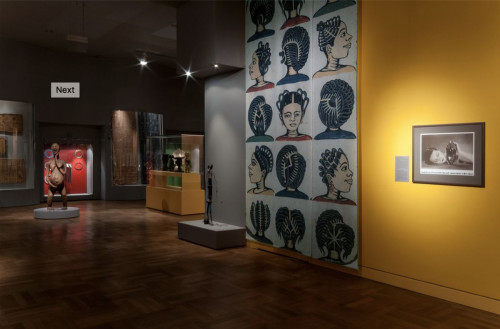 Museum Fünf Kontinente Ausstellung, dunkel gehalten mit Gemälden und Figuren in Glasvitrinen