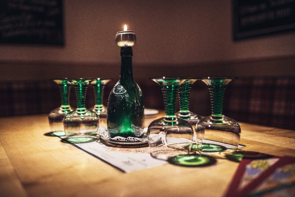 Ratskeller München, Weingläser stehen umgedreht auf dem Tisch, eine grüne Flasche auf der eine Kerze brennt
