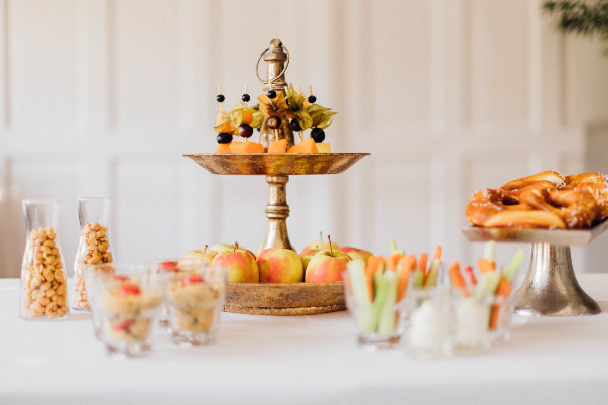 Schlosscafé im Palmenhaus, auf einem Tisch stehen verschiedene Etageren mit Obst, andere gefüllte Gläser stehen auf dem Tisch verteilt