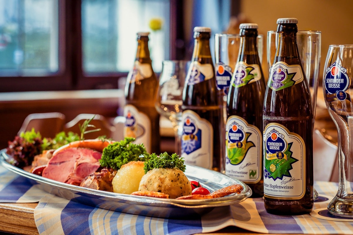 Schneider Bräuhaus, auf einem Tisch stheen vier Bierflaschen und ein Teller mit Knödeln und Fleisch, Brotzeit