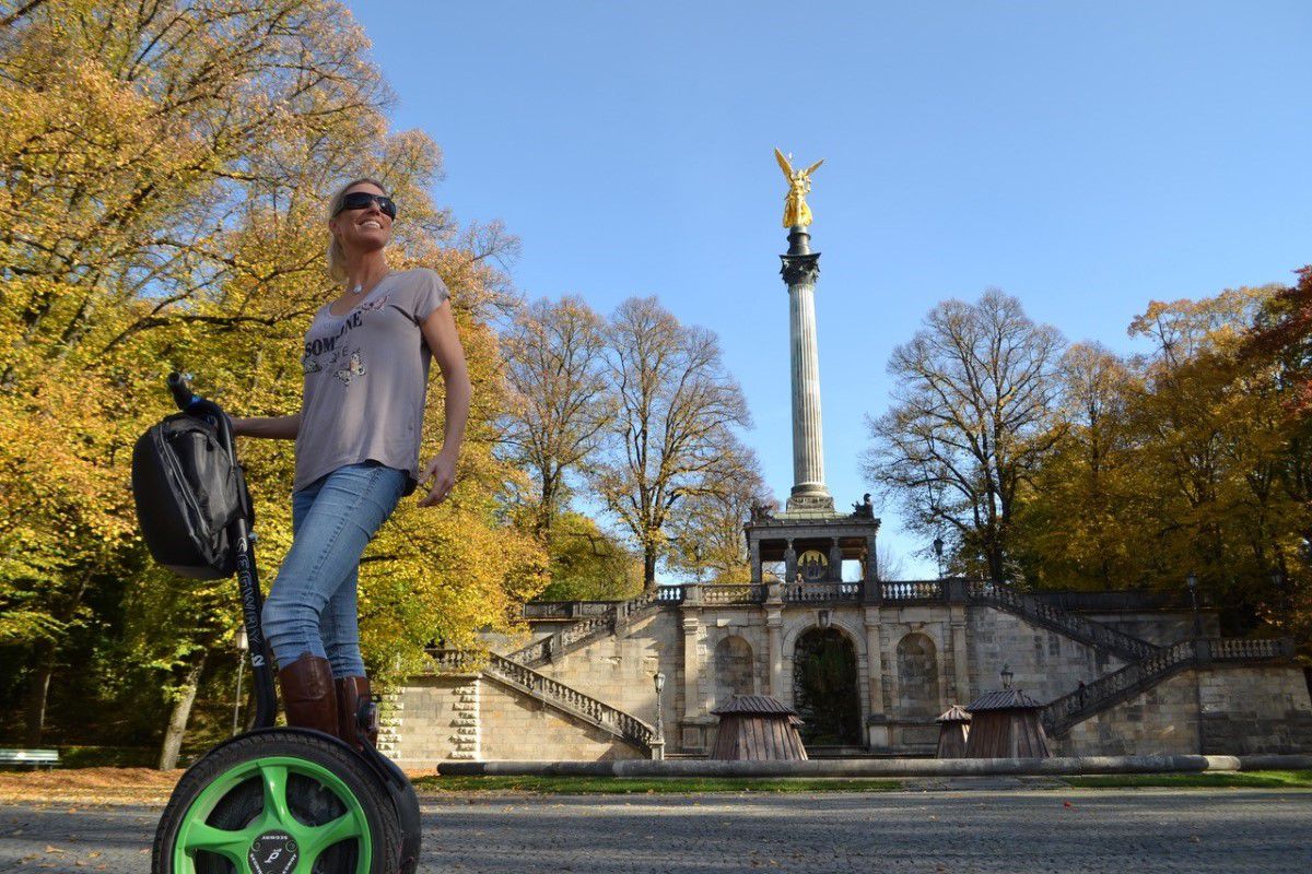 Seg to rent München, Tourist fährt auf einem Segway durch München, im Hintergrund ist eine Säule zu erkennen