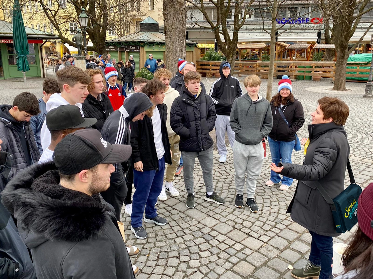 A school class is given a guided tour of the Viktualienmarkt by Servus Bavaria Tours
