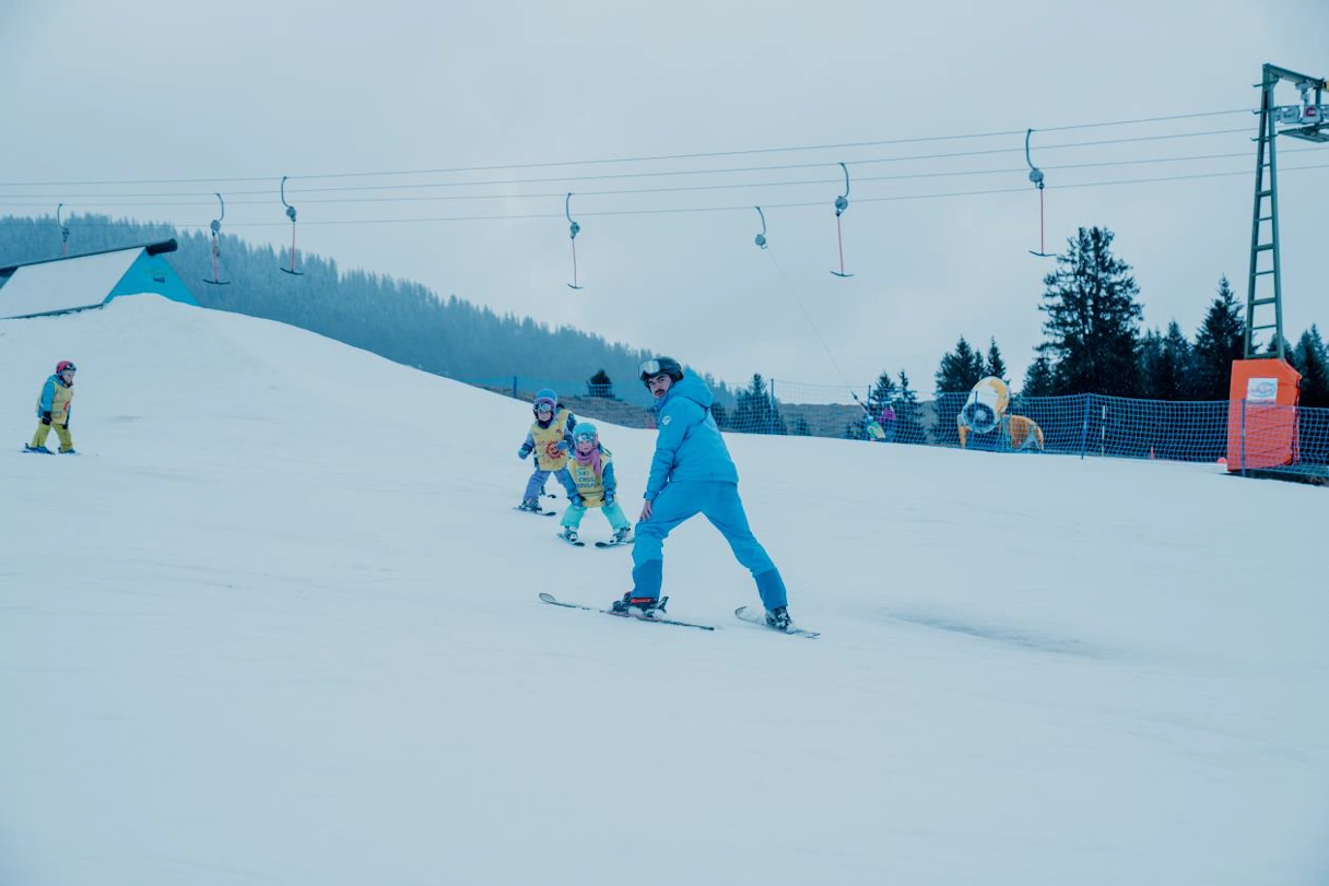 Young man on skis in Sudelfeld. In the background you can see a ski lift and small children on skis