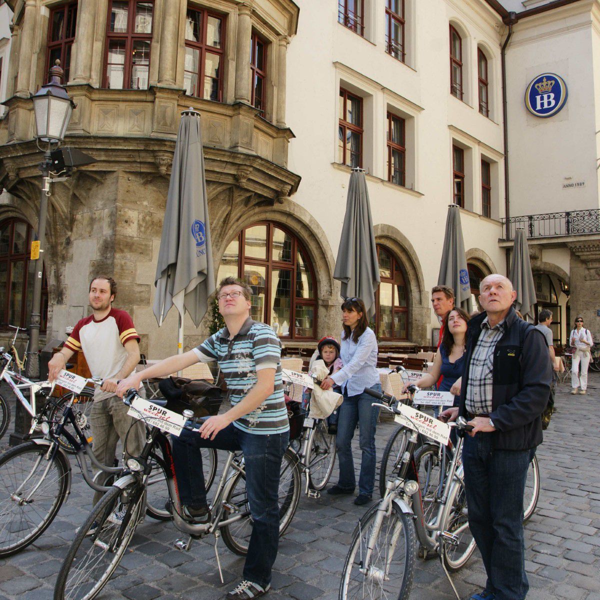 Gruppe mit Fahrrädern stehen vor dem Hofbräuhaus während ihrer Biertour und schauen nach oben