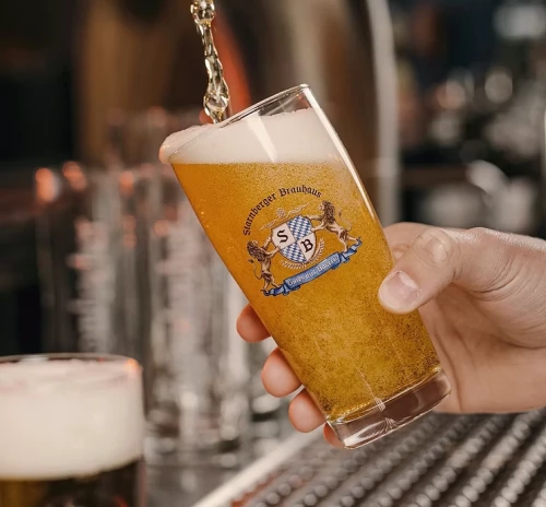 A glass of Starnberger beer (with the logo on the glass) is being freshly tapped.
