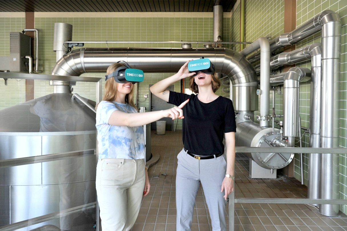 Zwei junge Frauen mit der TimeRide GO! VR Brille in einer Brauerei