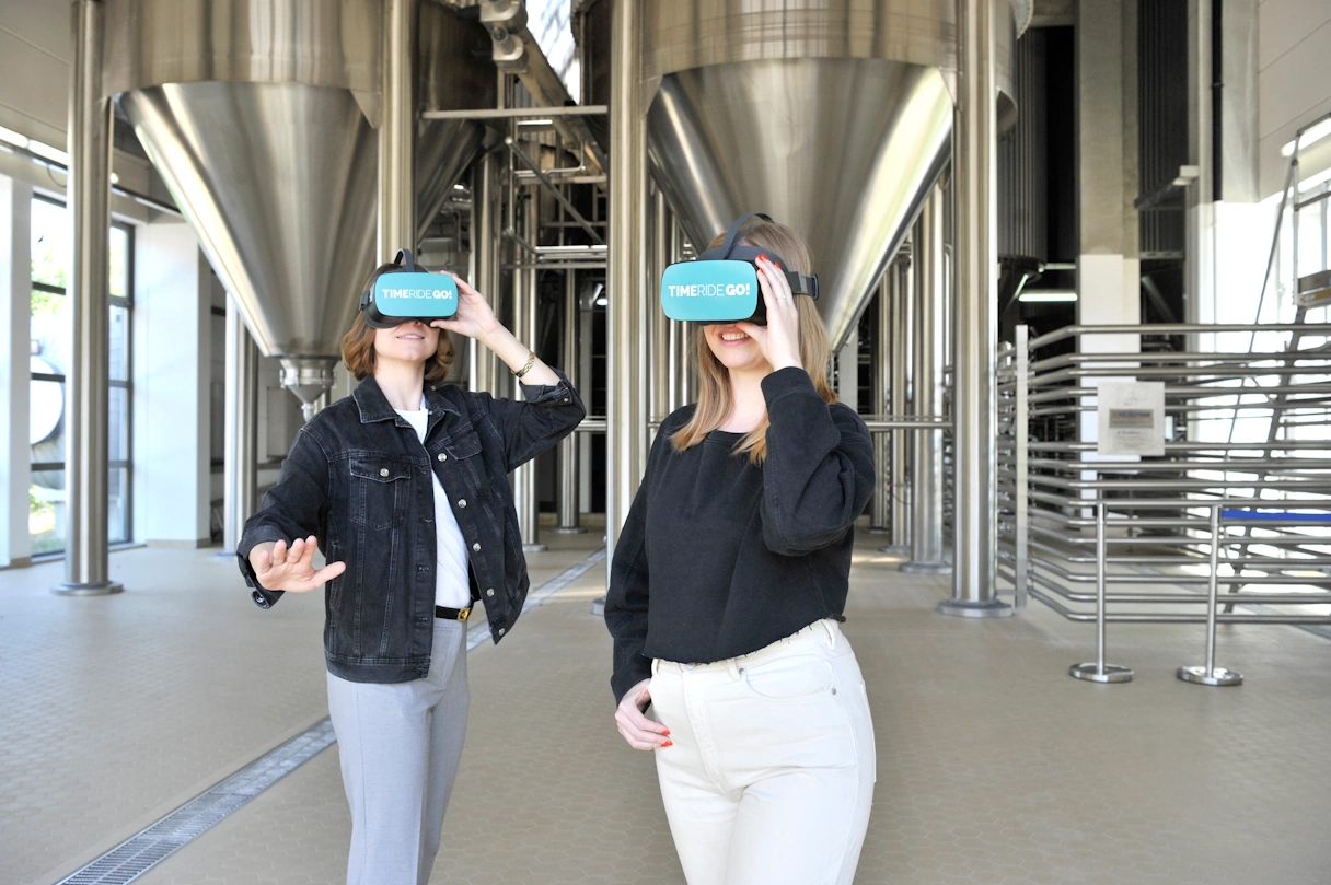 Zwei junge Frauen mit der TimeRide GO! VR Brille in einer Brauerei