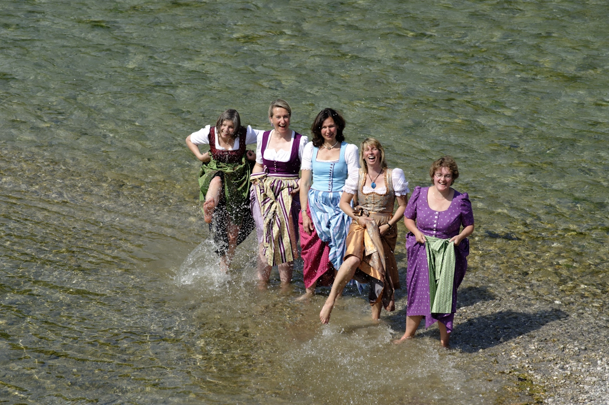 Die 5 Tölzer Stadtverführerinnen im Dirndl gekleidet in der Isar stehend.