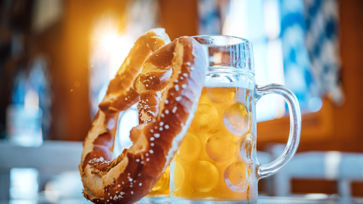 A beer stein with a large pretzel leaning against it