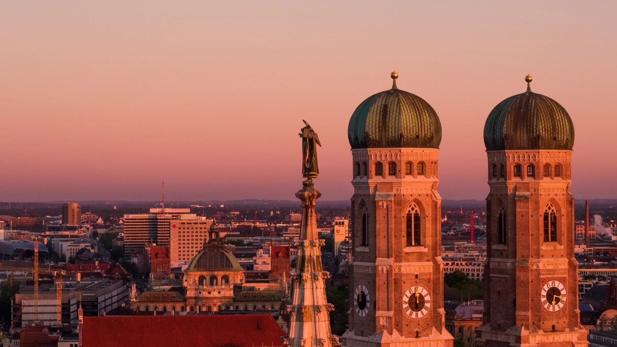 Blick über die Stadt München bei Sonnenuntergang mit Fokus auf die Türme der Frauenkirche und das Münchner Kindl