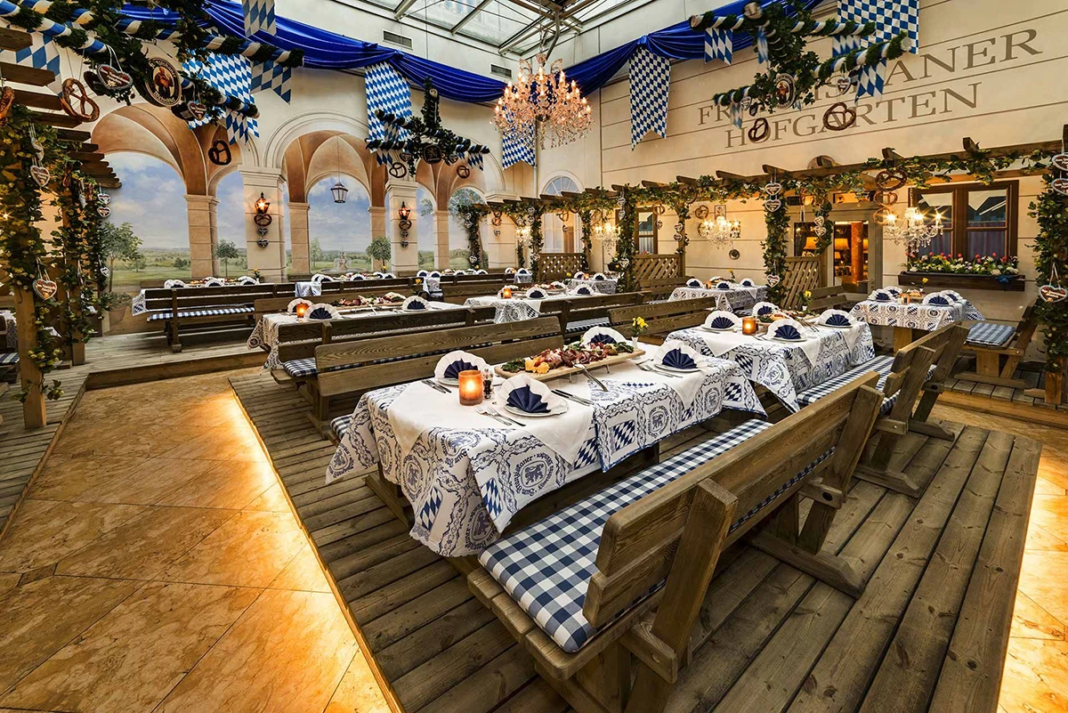 Zum Franziskaner, Innenraum, der wie ein Biergarten hergerichtet ist, Holztische und -Bänke, mit blau-weißen Tischdecken