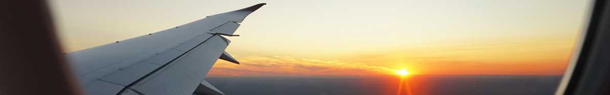 Blick aus dem Flugzeugfenster, Sonnenuntergang, orangener Himmel